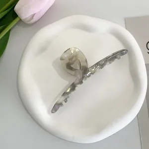 Detail of grey marble acetate hair claw clip on a white ceramic tray with tulips