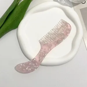 Pink acetate hair comb with mother-of-pearl texture on a white display tray