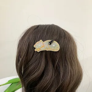 Details von süßer Katzen-Haarklammer mit Marmortextur und Perle auf braunem Haar