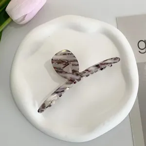 Detailed view of acetate marble hair claw clip in purple and grey on ceramic plate