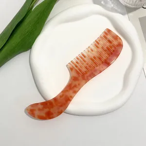 Macro detail of amber texture wide-tooth comb on white tray with tulip leaves
