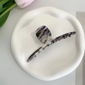 Detail of marble pattern acetate hair claw clip on decorative plate with pink tulip