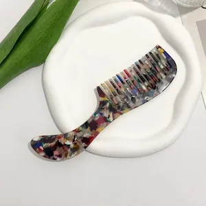 Top view of acetate hair comb with marble pattern on a white ceramic tray
