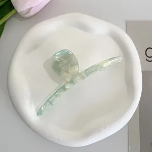 Close-up of mint green marble acetate hair claw clip on minimalist ceramic tray
