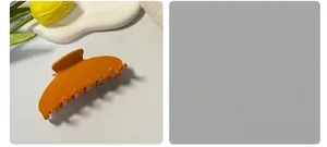 Detalle de una pinza de pelo naranja de acetato con mecanismo de resorte metálico fuerte