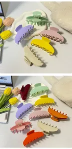 Vista de pinzas para el cabello grandes en colores mate macaron sobre mesa blanca
