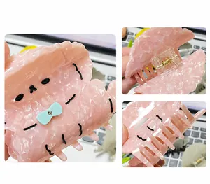 Detailed view of pink acetate hair claw with cartoon puppy design and golden spring