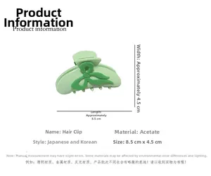 Detail showing an 8.5cm light green acetate hair claw clip with dark green bow decoration