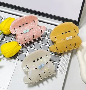 Close-up of three cute dog-shaped acetate hair claws with bow details on a keyboard