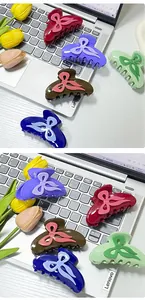 Close-up of bow-shaped acetate hair claws in various vibrant colors on a desk surface