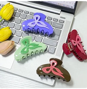 Detail view of four colorful bow-shaped hair claws on a desk with tulips decoration