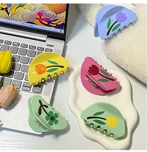 Dettaglio di mollette per capelli a tulipano in colori pastello giallo, rosa e menta