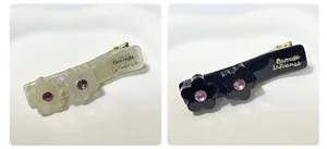 Dettaglio di fermagli per capelli floreali con strass neri e crema su ceramica