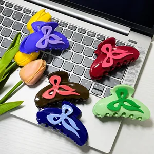 Five colorful bow-knot hair claw clips made of glossy resin on a modern silver laptop