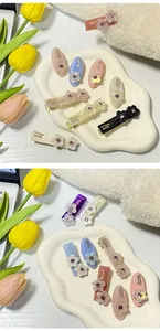 Dettaglio di fermagli per capelli in acetato con fiori e cristalli su vassoio bianco