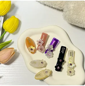 Dettaglio di un set da 7 fermagli in acetato con piccoli fiori e strass luminosi