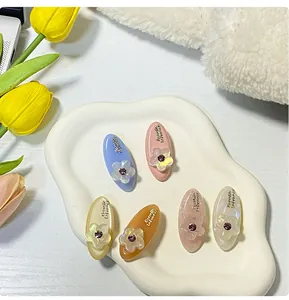 Dettaglio di fermagli per capelli ovali colorati con fiori in acrilico e strass viola brillanti