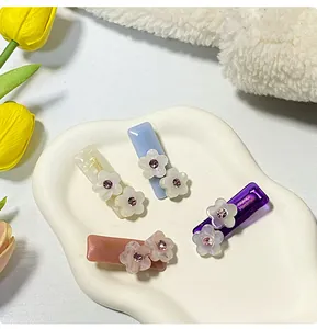 Vista macro di quattro fermagli per capelli a fiori con cristalli su un vassoio