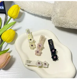 Dettaglio di quattro fermagli per capelli floreali in acetato con strass brillanti su vassoio