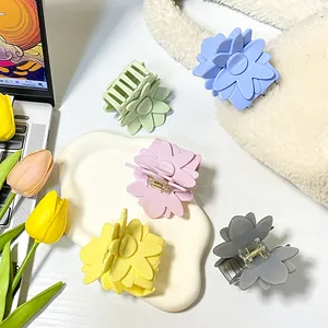 Pinces à cheveux fleurs en cinq tons pastels disposées sur un bureau esthétique