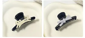 Detail view of mini hair clips featuring a cute cream cat and a grey bow tie on black resin