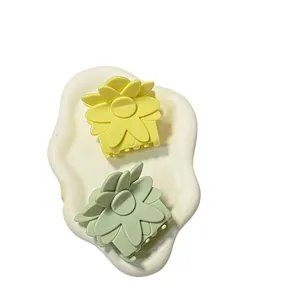 Lot de deux pinces à cheveux fleurs mates jaune et vert sur plateau blanc