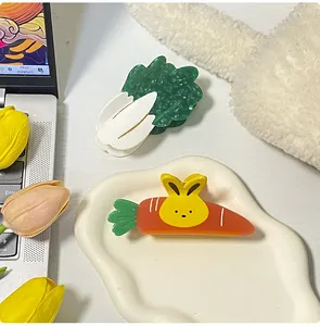 Dettaglio delle pinze per capelli in acetato a forma di carota e cavolo su una scrivania