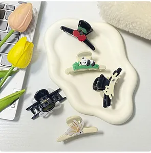 Selection of cute panda and cherry resin hair clips on a white tray with tulip decor