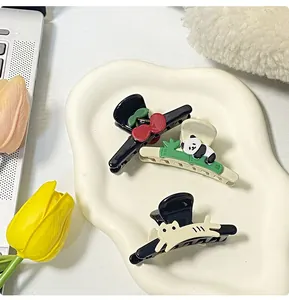 Detailed view of three cute panda, cherry, and cat hair clips on a white ceramic tray
