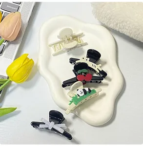 Detailed view of cute panda and cherry acrylic hair clips on a white display tray