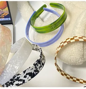 Close-up of four checkerboard and marble pattern headbands on a soft white plush surface