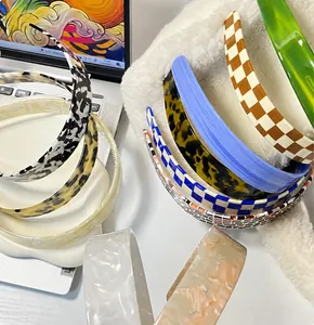 Detail shot of checkered and leopard resin headbands on a white plush surface