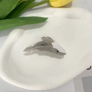 Close-up of whale-shaped acetate hair claw clip with grey texture on a ceramic tray