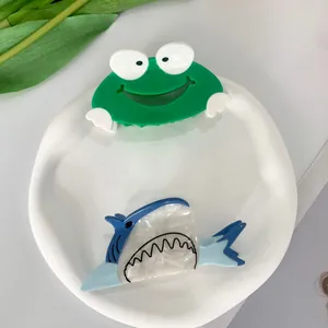 Schattige haarklemmen van kikker en haai van hoogwaardig acetaat op wit plateau