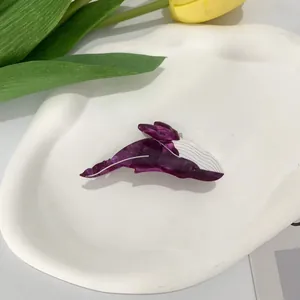 Macro shot of purple acetate orca hair claw clip on an artistic ceramic white plate