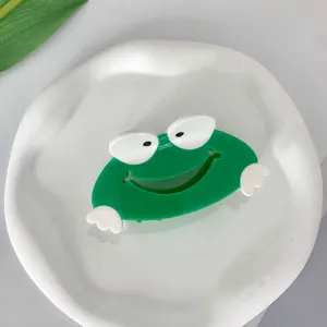 Leuke groene kikker haarklem van acetaat, bovenaanzicht op een wit plateau