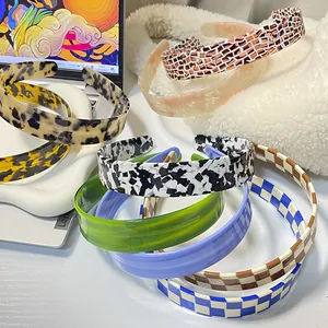 Collection of retro checkered and marble pattern headbands on a white desk