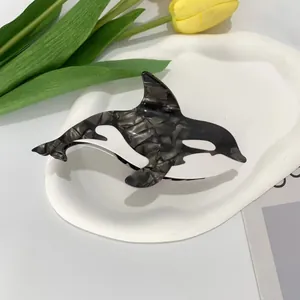 Detail of orca shaped acetate hair claw clip with marble texture on decorative plate