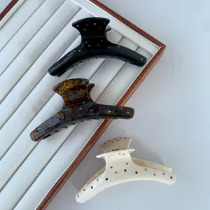 Three acetate hair claws in black, tortoiseshell and cream with colorful rhinestones