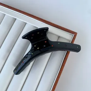 Elegant black acetate hair claw clip with colorful rhinestones on a jewelry tray