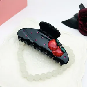 Detailaufnahme der schwarzen Haarklammer mit Kirschdesign und rosa Strasssteinen