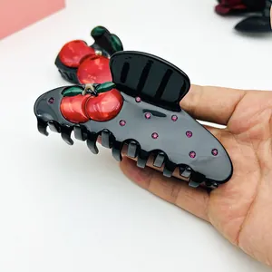 Nahaufnahme einer großen schwarzen Haarklammer mit 3D-Kirschen und rosa Strasssteinen