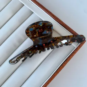 Macro view of acetate hair claw clip with colorful rhinestones and tortoiseshell texture