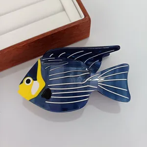 Pince à cheveux en forme de poisson bleu en acétate avec détails jaunes sur support blanc
