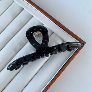 Detail of black acetate hair claw clip with colorful rhinestones in a white gift box