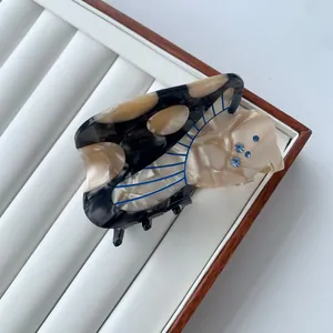 Gros plan sur une pince à cheveux en acétate écaille avec strass bleus et motifs gravés