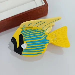 Détail d'une pince à cheveux poisson tropical avec motifs jaunes et bleus en acétate