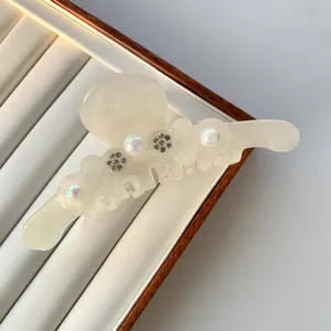 Nahaufnahme der cremeweißen Acetat-Haarklammer mit eleganter Perle und Strassblume