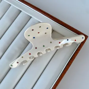 Detail of cream acetate hair claw clip featuring colorful rhinestones for women
