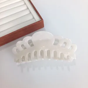 Macro detail of a 14cm pearlescent white acetate hair claw clip with a hollow crown design
